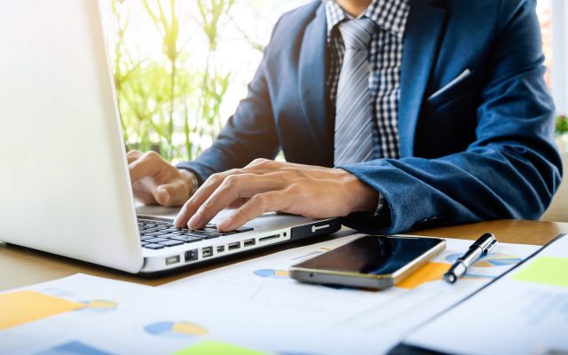 Business man working at office with laptop, tablet and graph data documents on his desk